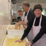 Männer panieren Fischfilets in großen Wannen in einer Küche.