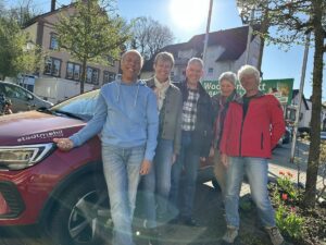 Fünf ehrenamtliche Fahrer:innen des Angelloch-Mobils stehen lächelnd neben einem roten Stadtmobil-Auto in Gauangelloch
