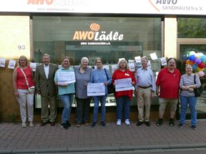 Gruppenbild vor dem AWO-Lädle Sandhausen mit Vertretern des Lions Club Leimen und drei lokalen Hilfsorganisationen, die Spendenschecks überreicht bekommen.