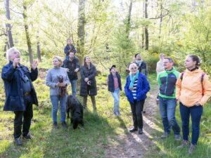 Gruppe von Teilnehmern lauscht bei Vogelstimmenwanderung im Wald den Erklärungen von Prof. Dr. Michael Wink.