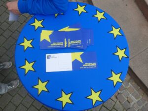 Blauer Tisch mit EU-Sternen und mehreren Postkarten zum Europatag.