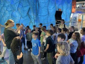Kinder hören einer Referentin in der Ausstellung der KLIMA ARENA aufmerksam zu