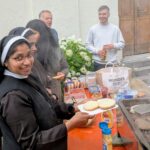 Schwester mit Burgerbrötchen am Grill beim Gemeindefest.