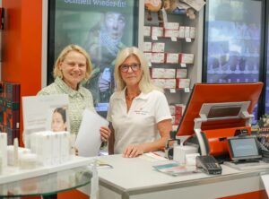 Christiane Staab und Monika Herzog stehen in einer Apotheke im Gespräch, Thema ist die Lage der Apotheken zum Tag der Apotheke 2025.