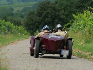 Historische Rallyefahrzeuge auf Landstraße mit Weinbergen im Hintergrund bei der Heidelberg Historic