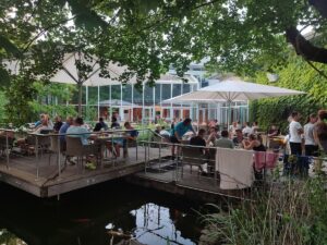Gäste sitzen am Abend auf der Terrasse des Restaurants Amici mit Blick auf den Teich.