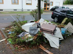 Haufen aus Möbelresten, Koffer und Müllsäcken in einem Wohngebiet